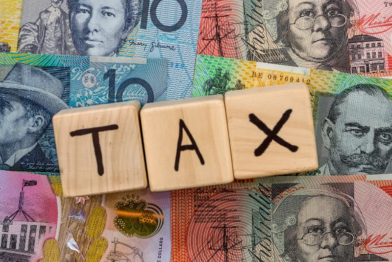 Australian dollar banknotes with wooden TAX blocks for FEIE versus FTC planning